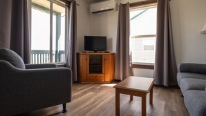A living room with a television on a wooden cabinet, a grey sofa, and a wooden coffee table.