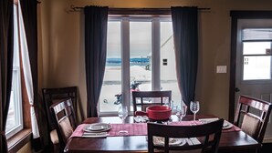 A dining table set with chairs, a red pot, and wine glasses.