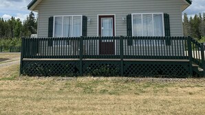 A single-story house with a gabled roof, a front door, and a small porch with a black picket fence.