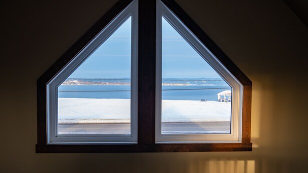 A window with a view of a beach and a distant building.