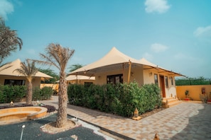 A hotel with multiple rooms, each with a covered patio and a view of the surrounding greenery.