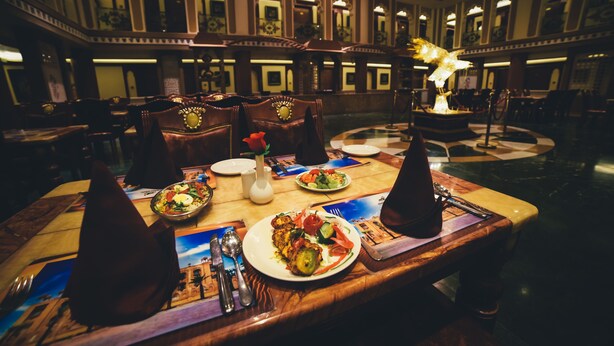 A dining area with tables set for meals, chairs, and a chandelier. - Chokhi Dhani The Palace Hotel (Jaisalmer)