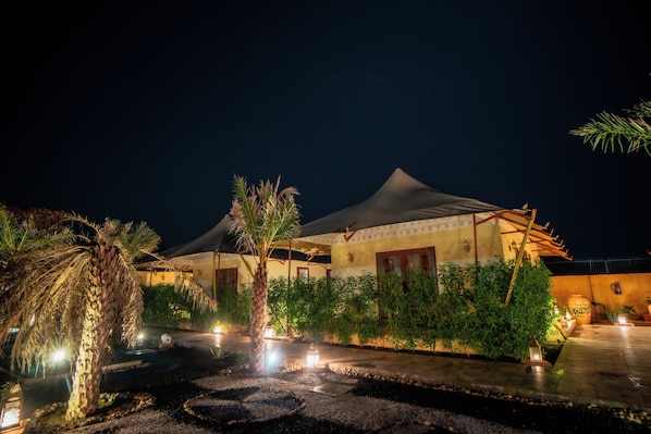 A building with a covered patio area, surrounded by greenery and a small water feature.