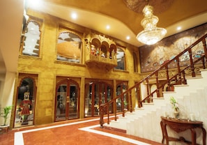 Un interior imponente con una escalera, arcos ornamentales y un candelabro.