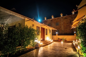 A courtyard with a tiled floor, potted plants, and a building with a balcony.