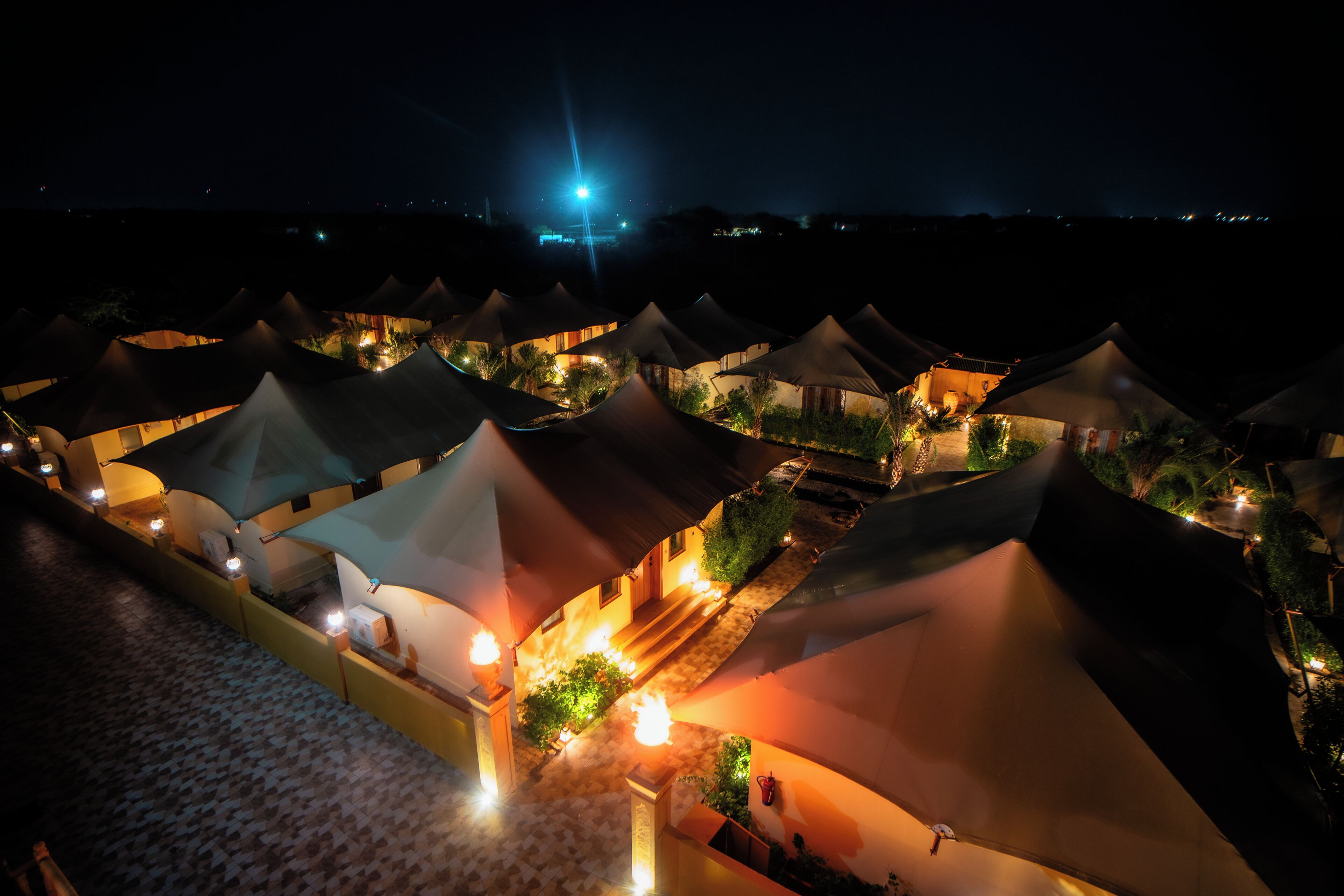 A series of tents with warm lighting, arranged in a row with pathways between them.