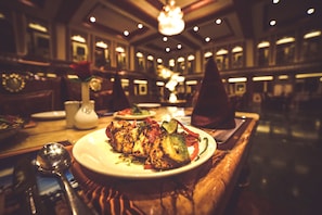 A dining table with plates of food, a vase with a rose, and a spoon. - Chokhi Dhani The Palace Hotel (Jaisalmer)