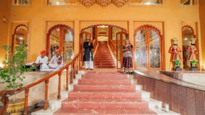 A grand staircase with ornate railings leading to a high-ceilinged hall.
