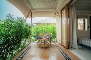 A balcony with a table and chairs, surrounded by greenery. - Chokhi Dhani The Palace Hotel (Jaisalmer)