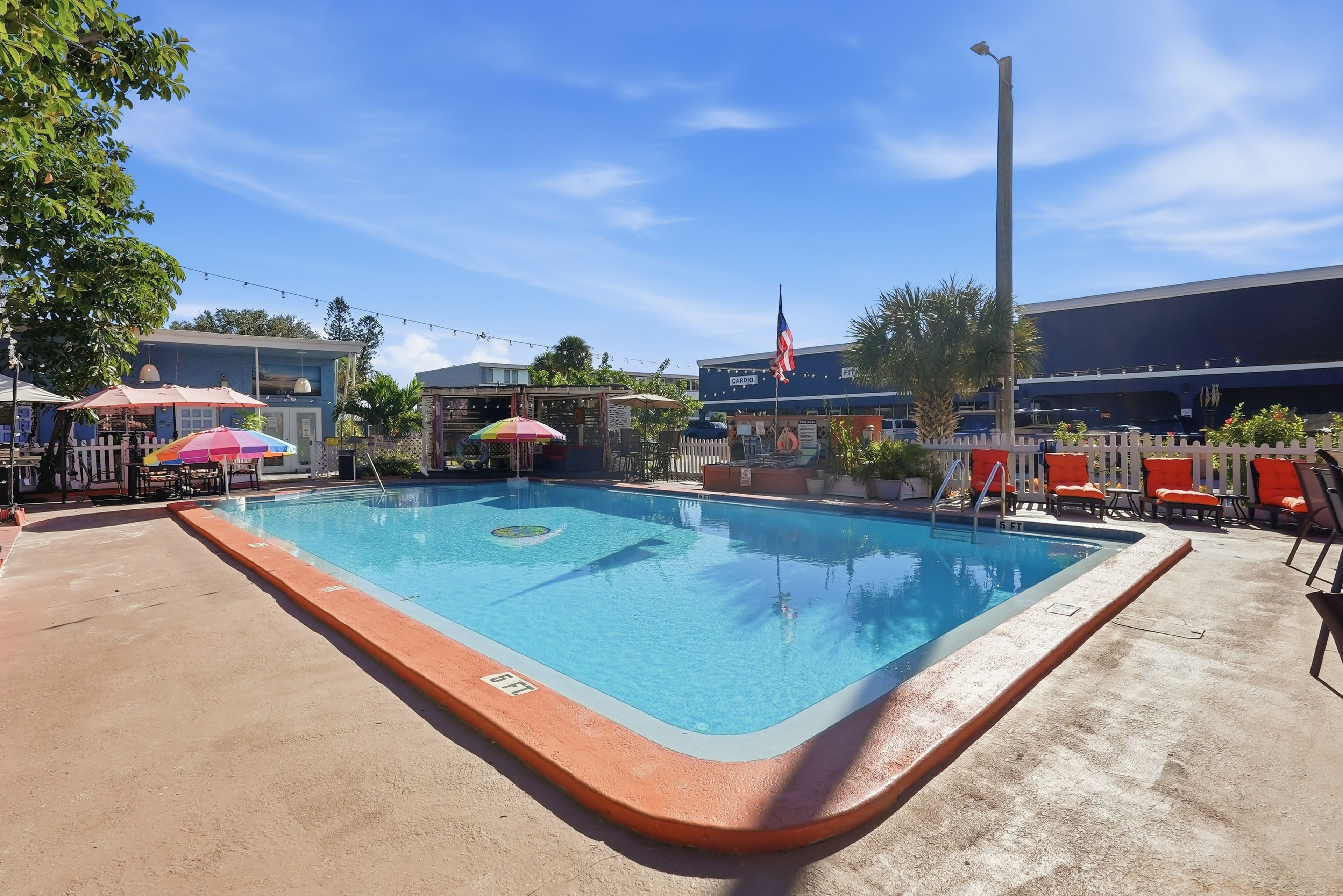 A swimming pool with a 5 ft depth marker, surrounded by lounge chairs and umbrellas.