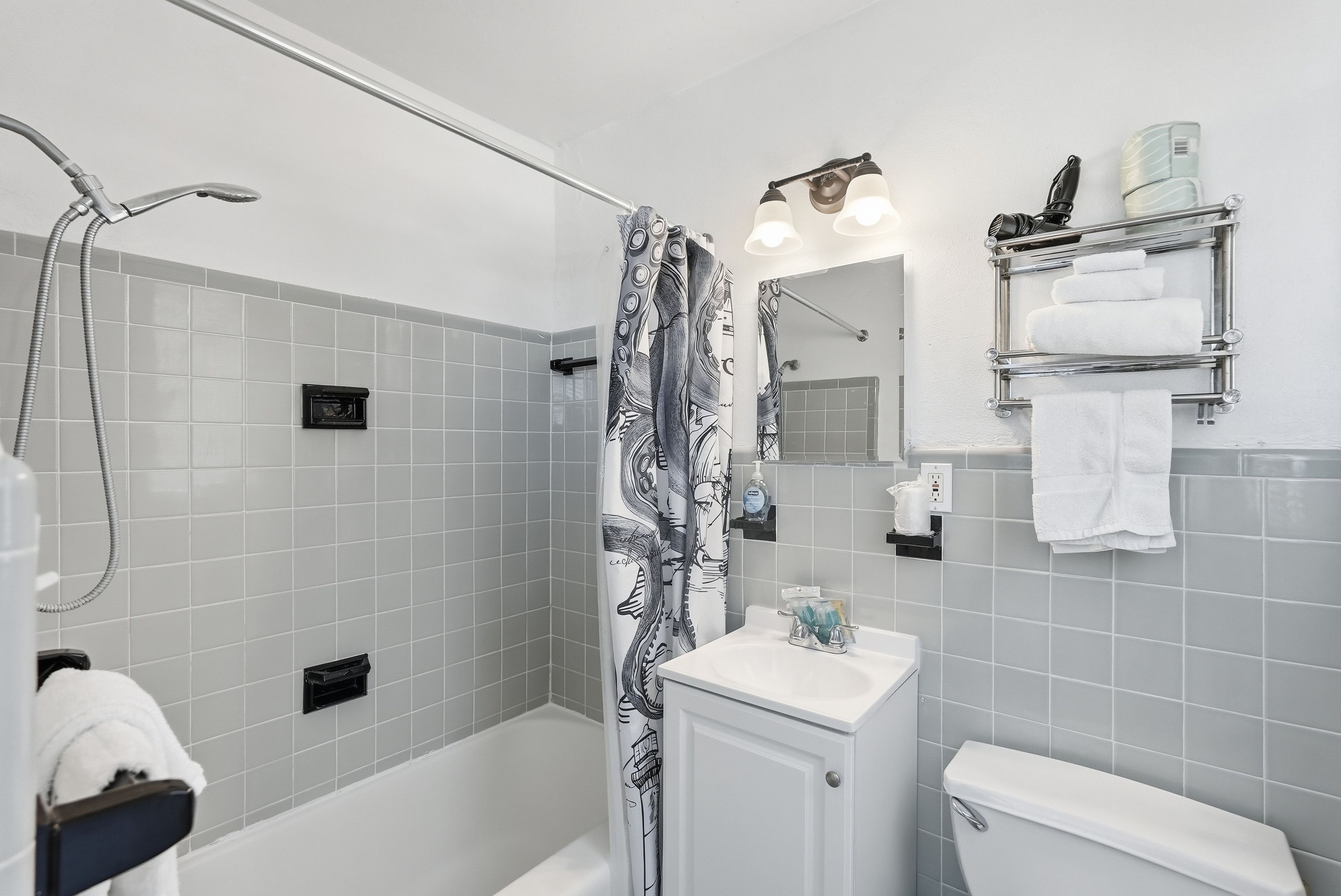 A bathroom with a shower, toilet, sink, and towel rack.