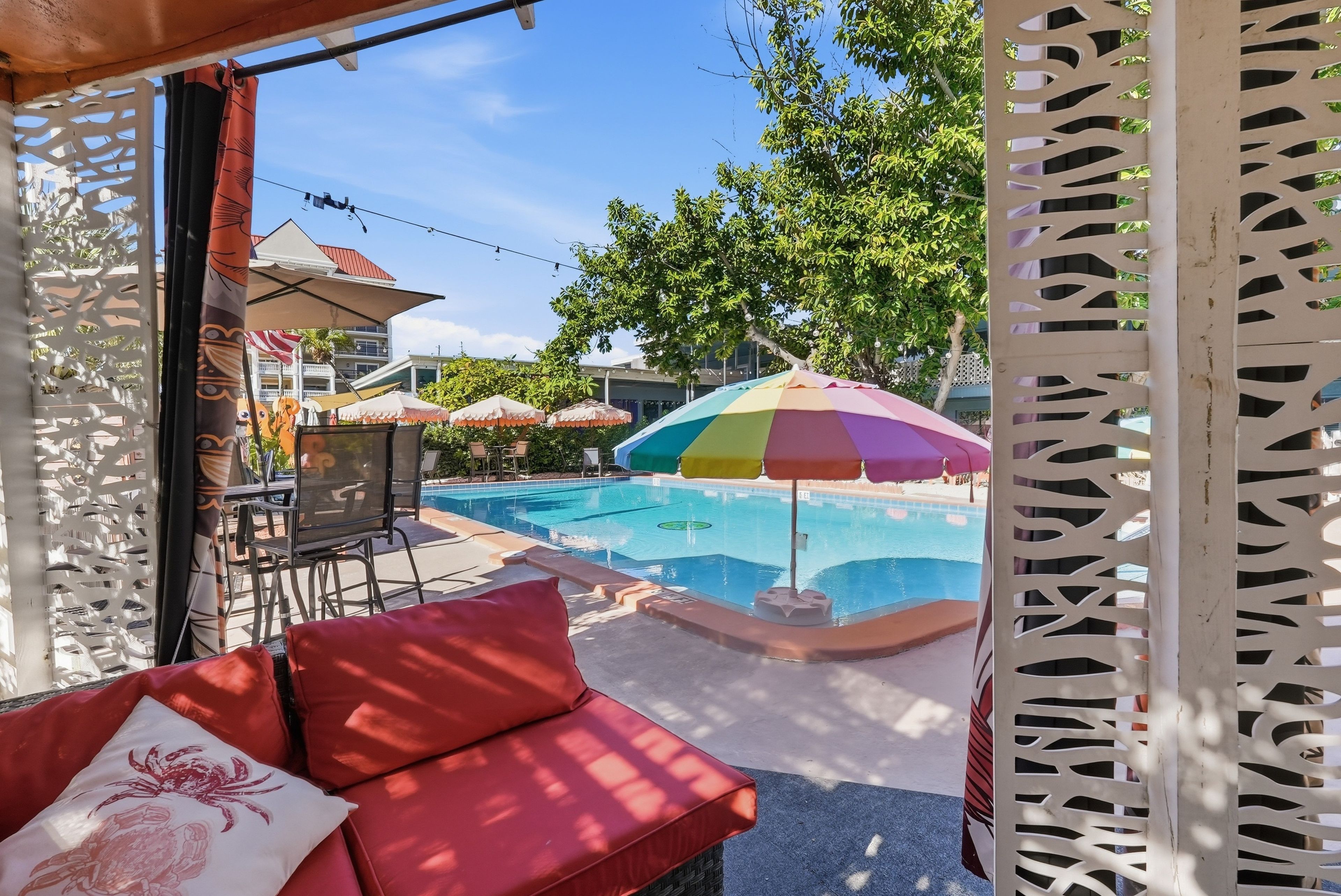 Un espace piscine avec un canapé rouge et des parasols.