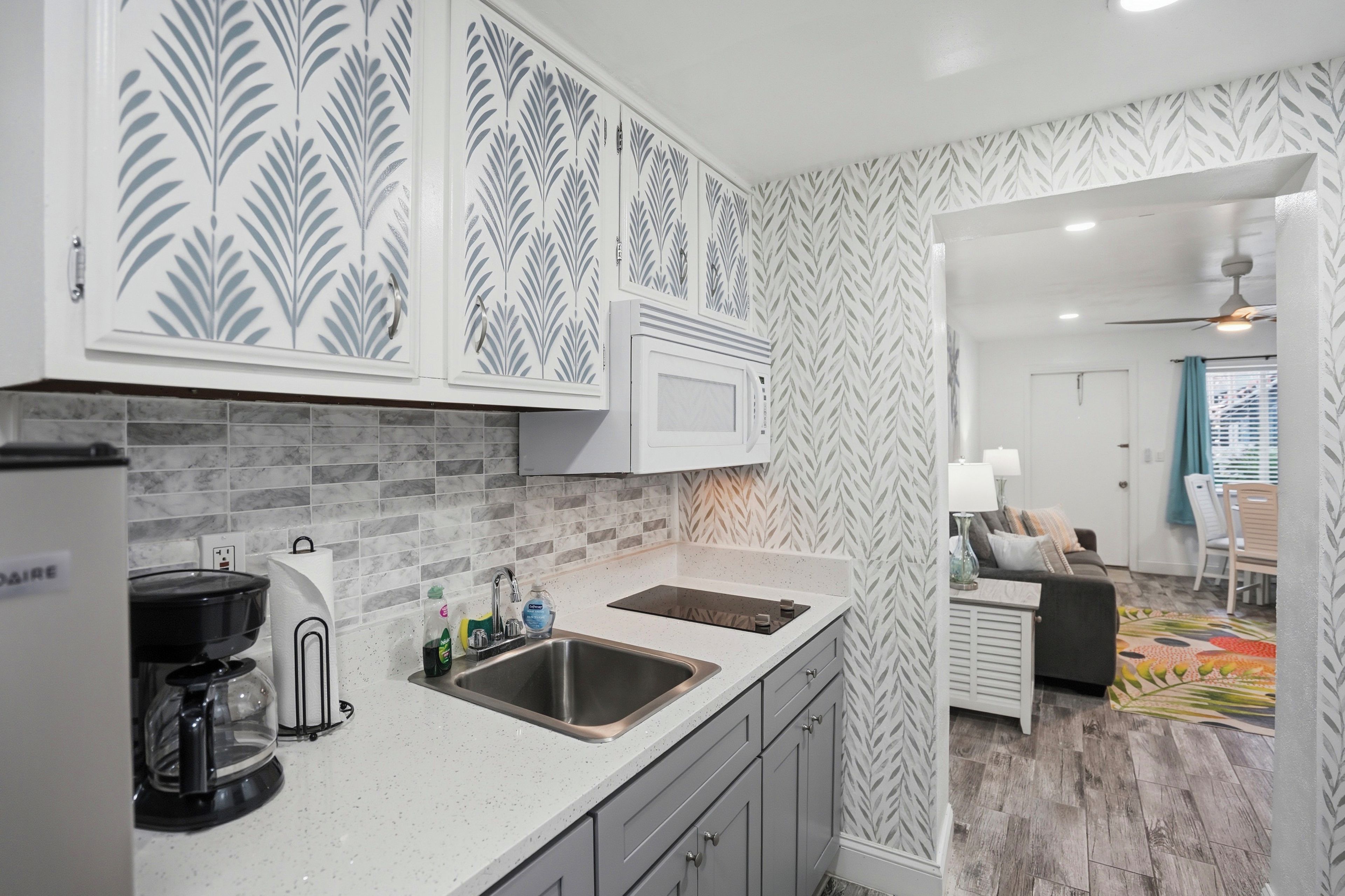 A modern kitchen with a double sink, a coffee maker, and a microwave.