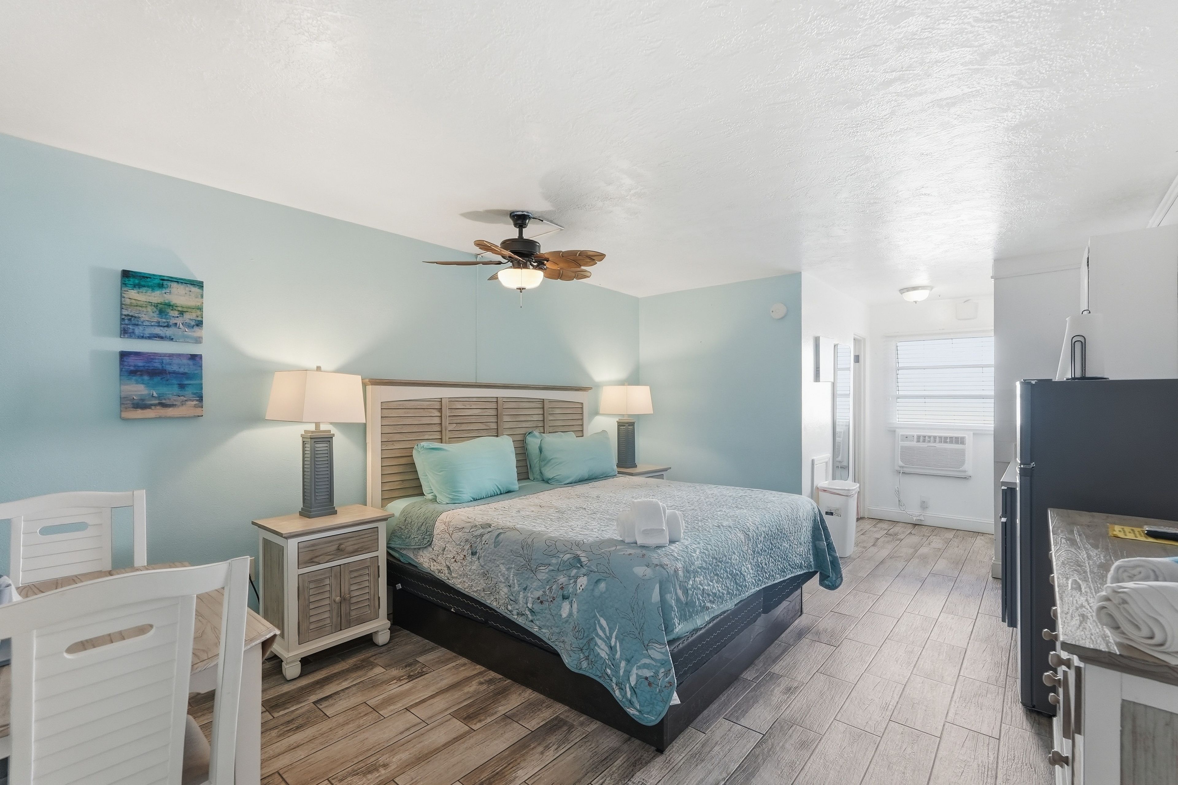 A bedroom with a bed, two bedside tables, a ceiling fan, and a window.