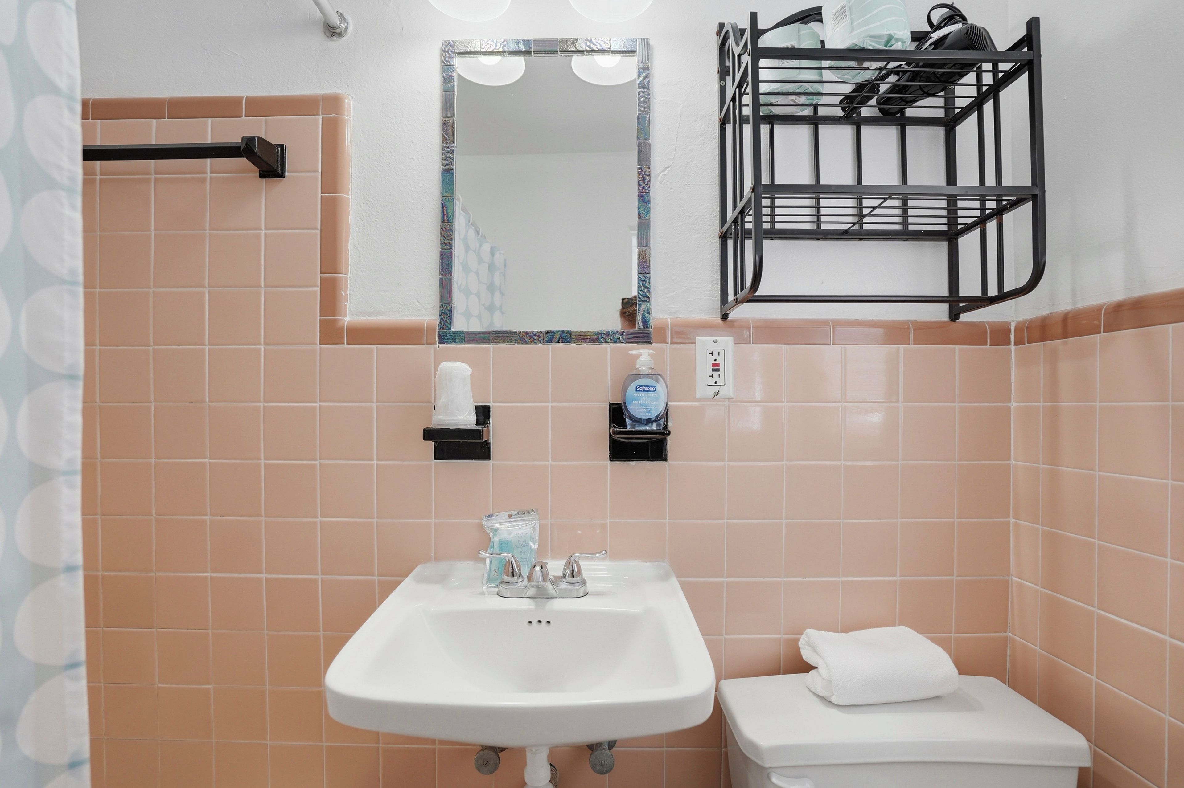 Une salle de bain avec un lavabo blanc, des toilettes, un miroir et un porte-serviettes.