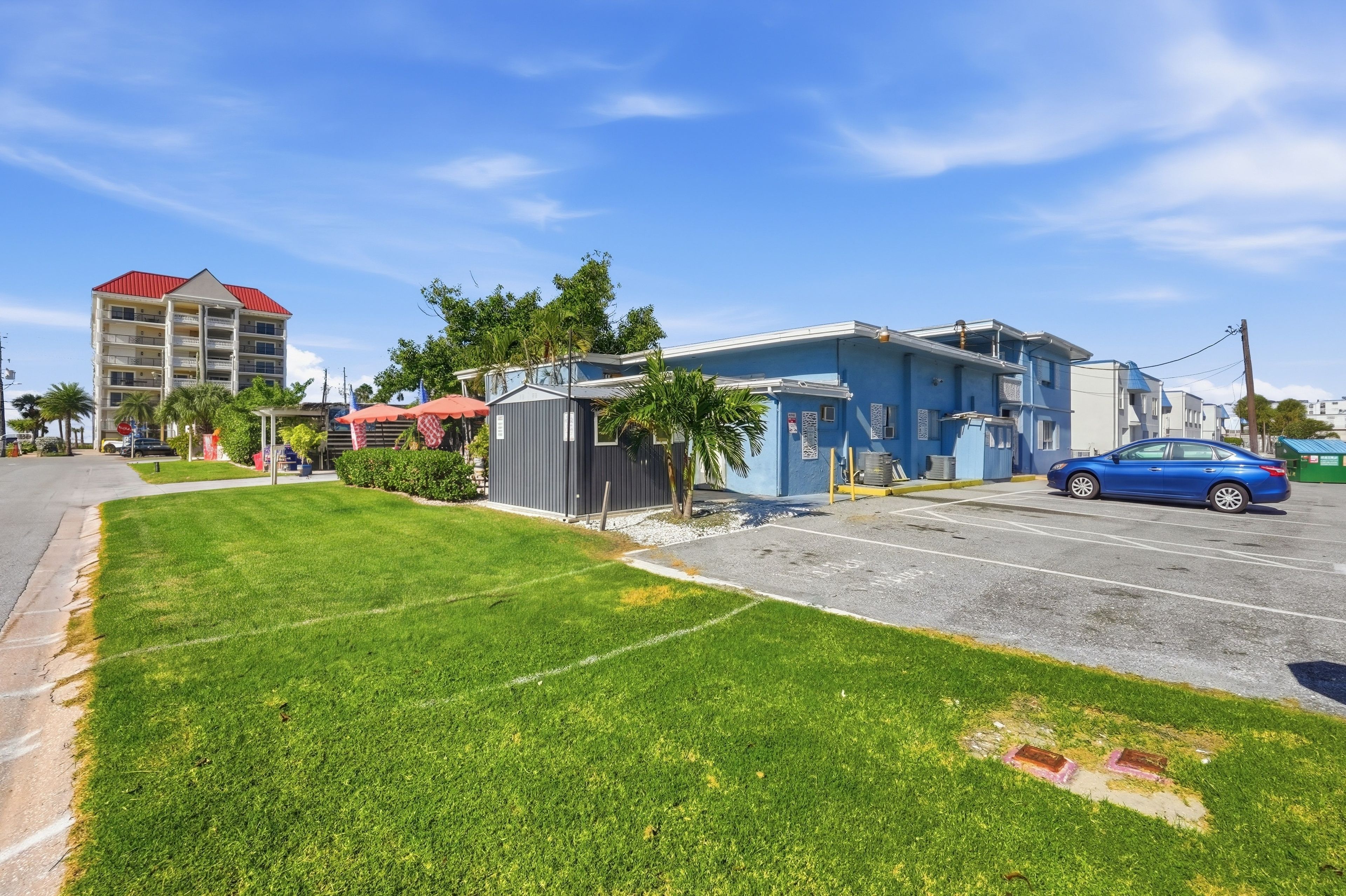 Un quartier résidentiel avec un immeuble bleu, un immeuble d’appartements avec un toit rouge et un parking.
