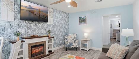 A living room with a fireplace, a ceiling fan, a television, and a sofa.