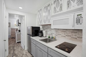 A modern kitchen with a microwave, coffee maker, and a sink.