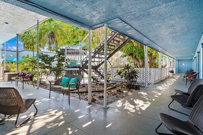 A covered outdoor area with seating, a staircase, and a view of the surrounding greenery. - Malibu Resort Motel (North Redington Beach)