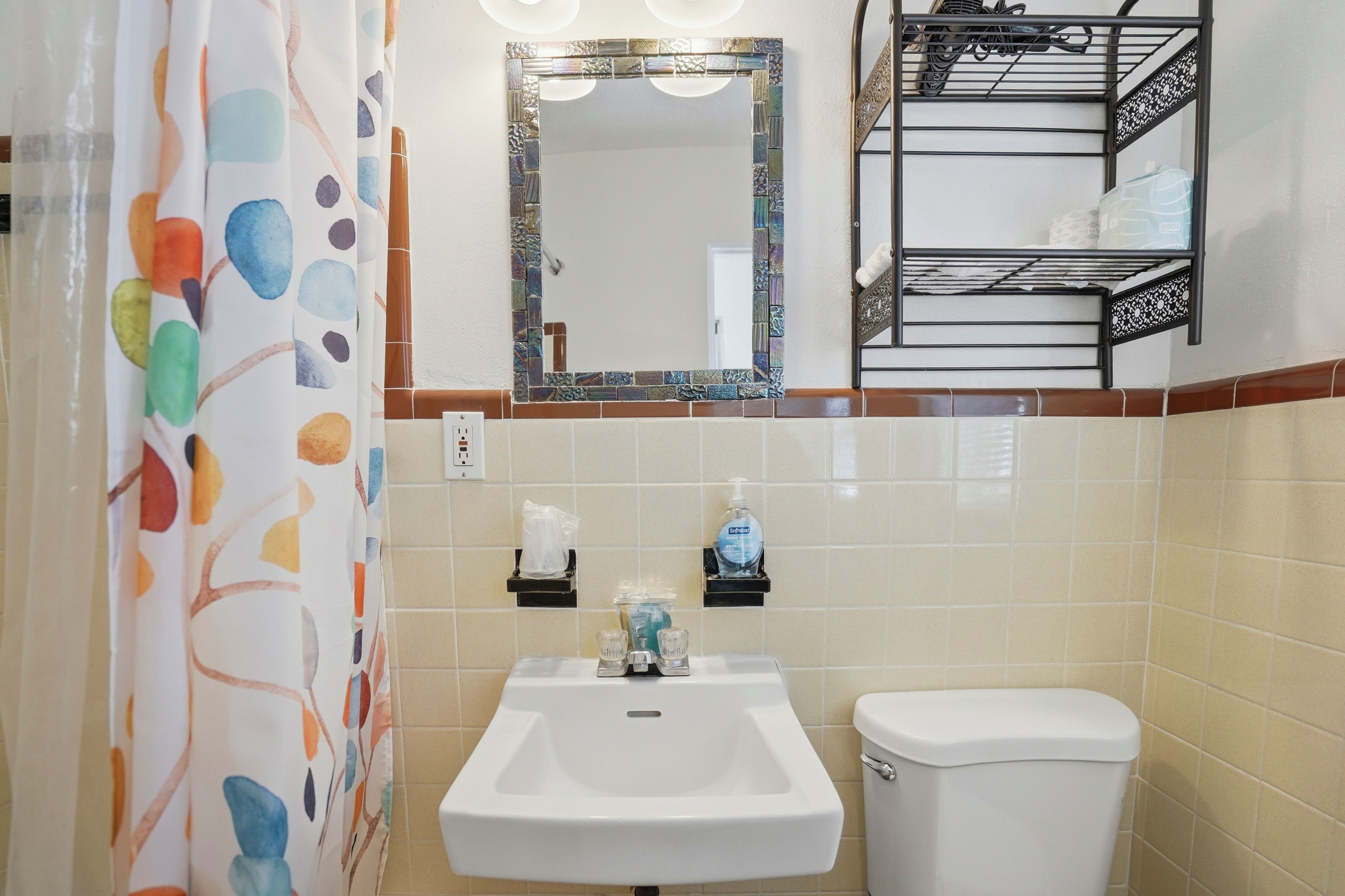 Une salle de bain équipée d’un lavabo, de toilettes, d’un miroir et d’un porte-serviettes.