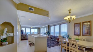 A spacious kitchen with a central island, a dining area with a chandelier, and large windows providing natural light. - Gulf Crest Condominiums (Panama City Beach)