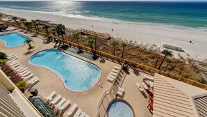 A pool area with two swimming pools, sun loungers, and a wooden deck. - Gulf Crest Condominiums (Panama City Beach)