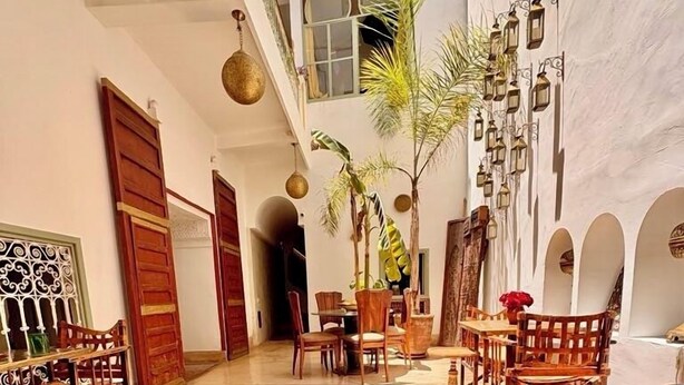 A spacious courtyard with a round glass table, red roses, and a book titled 'Marrakesh'. - Riad La Cigale (Marrakech)