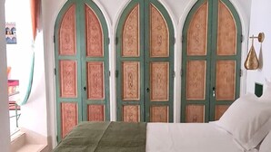 A bedroom with a bed, a green carpet, and three arched doors with intricate designs. - Riad La Cigale (Marrakech)