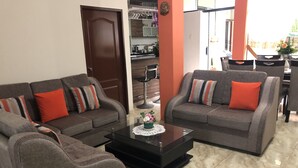 A living room with two grey sofas, a coffee table, and a dining area with chairs. - B&B Cusing Wasi (Callao)