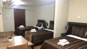 A hotel room with two beds, a wooden table, and a small potted plant. - B&B Cusing Wasi (Callao)