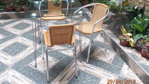 A patio area with a glass table and wicker chairs, surrounded by potted plants and a brick wall. - B&B Cusing Wasi (Callao)
