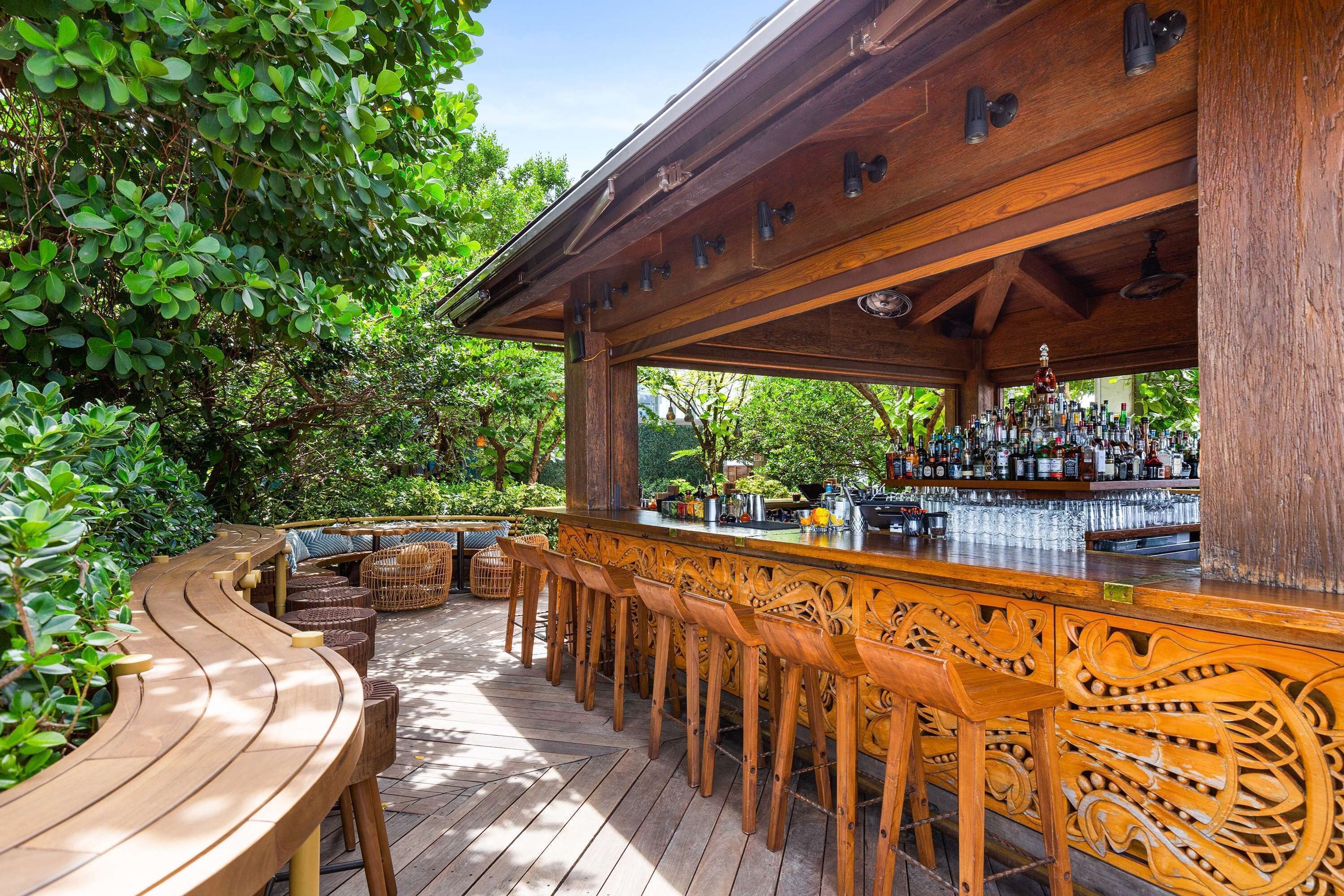 An outdoor bar area with wooden bar stools and a bar counter.