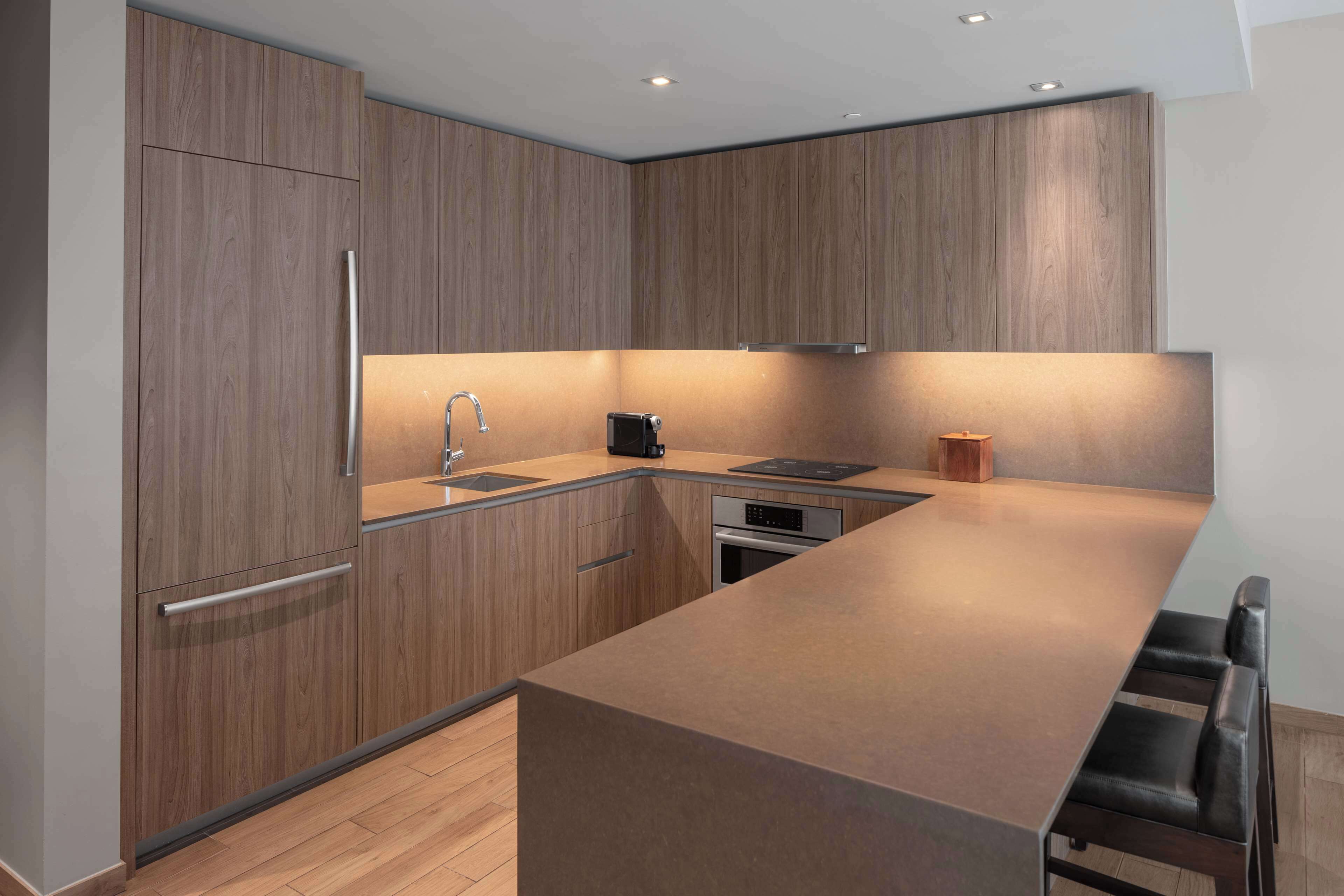 A modern kitchen with wooden cabinetry, a stainless steel sink, and a built-in oven.