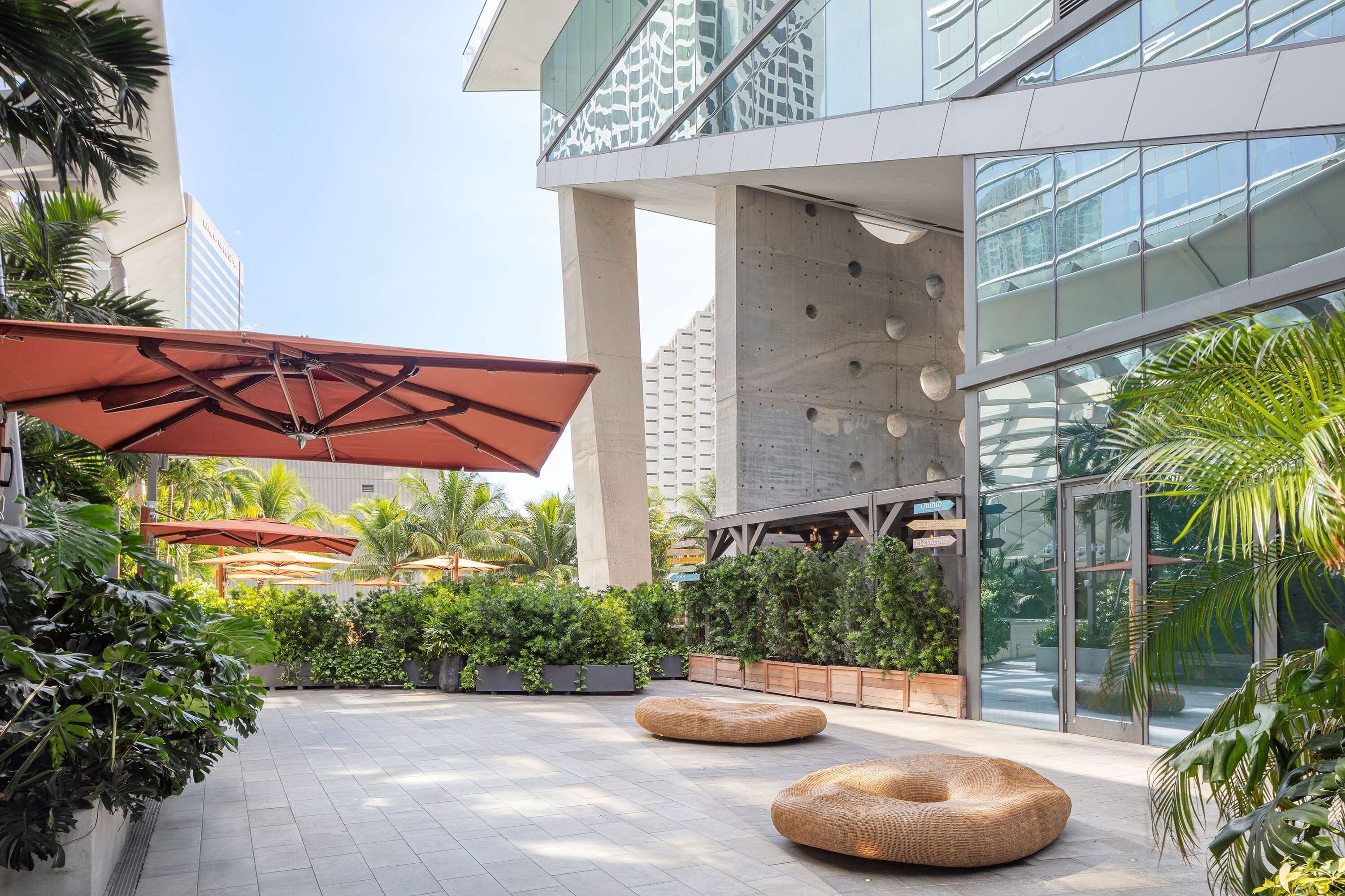 Un espace extérieur moderne comprenant un coin salon, des jardinières et une façade en verre.