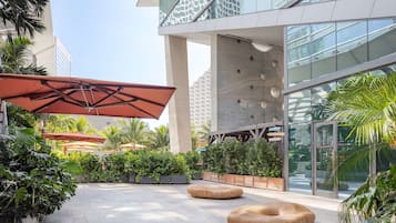 A modern outdoor area with a seating area, planters, and a glass building facade.