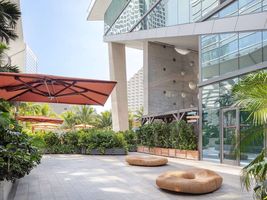 A modern outdoor area with a seating area, planters, and a glass building facade.