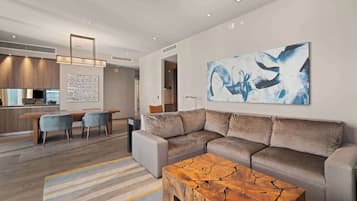 A modern living room with a sectional sofa, a coffee table, and a large abstract painting on the wall.
