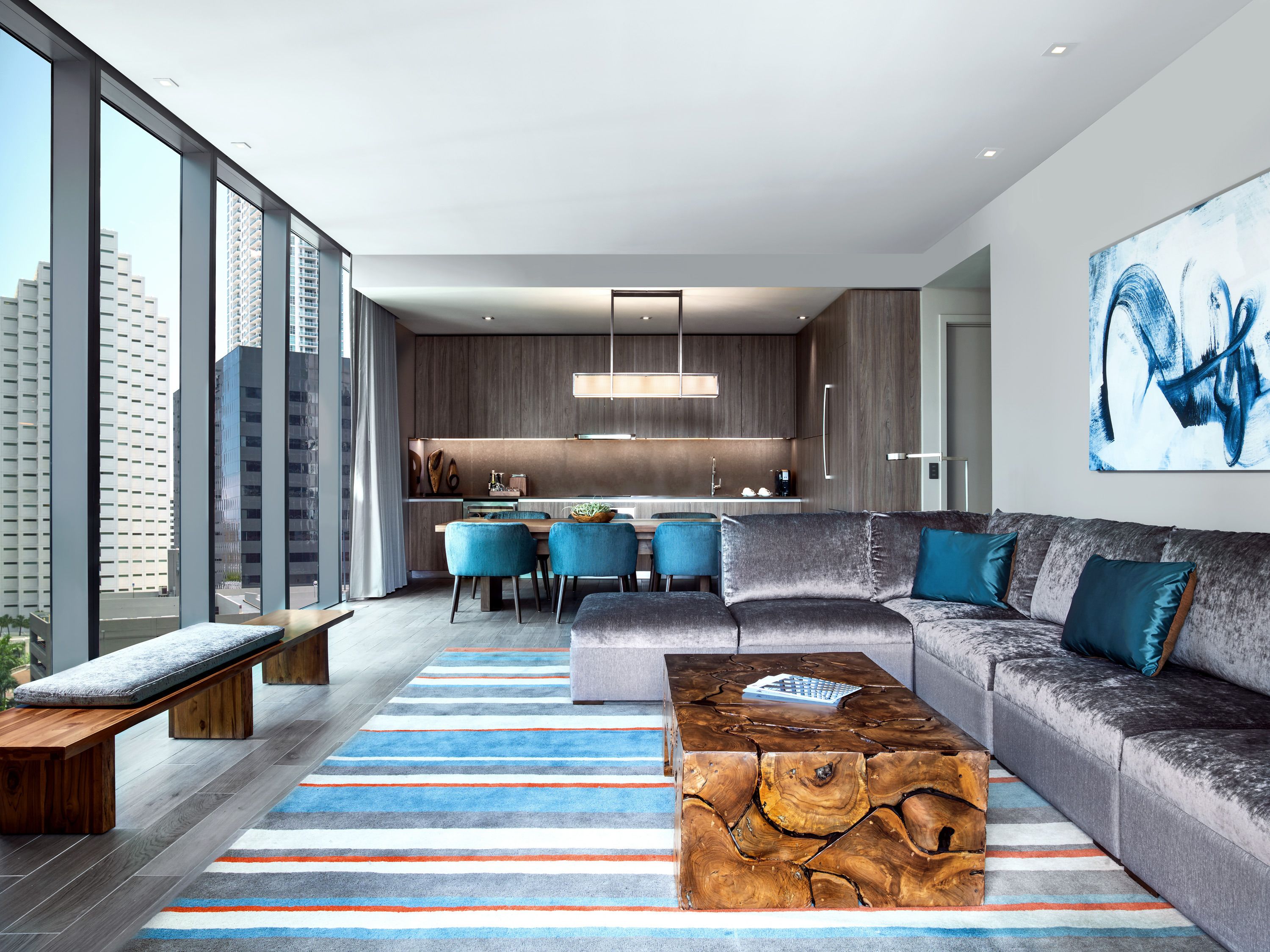 Ein modernes Wohnzimmer mit einer Couch, einem Couchtisch und einem Essbereich mit Stühlen sowie einer Küche im Hintergrund.