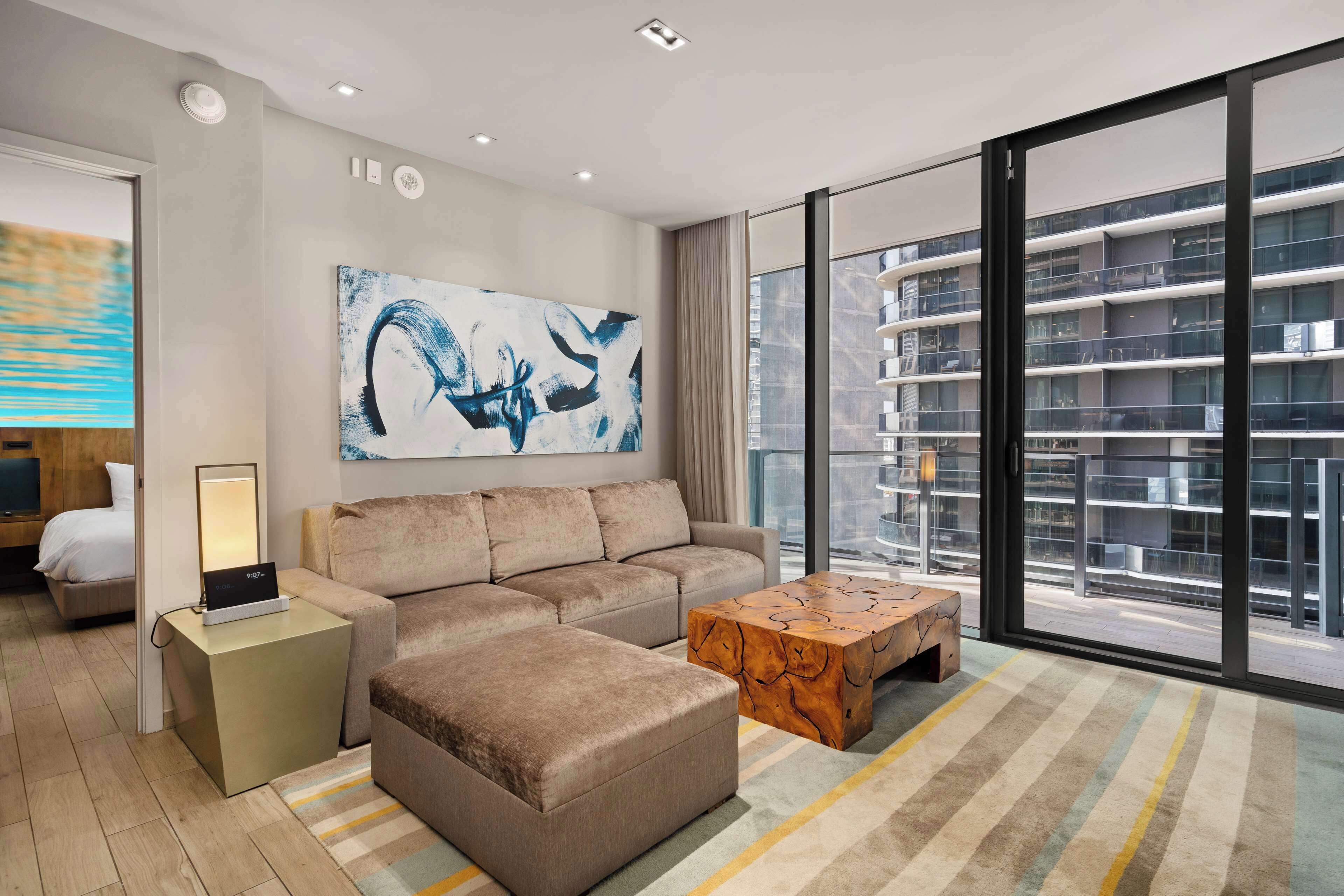 A modern living room with a sofa, ottoman, coffee table, and artwork on the wall.