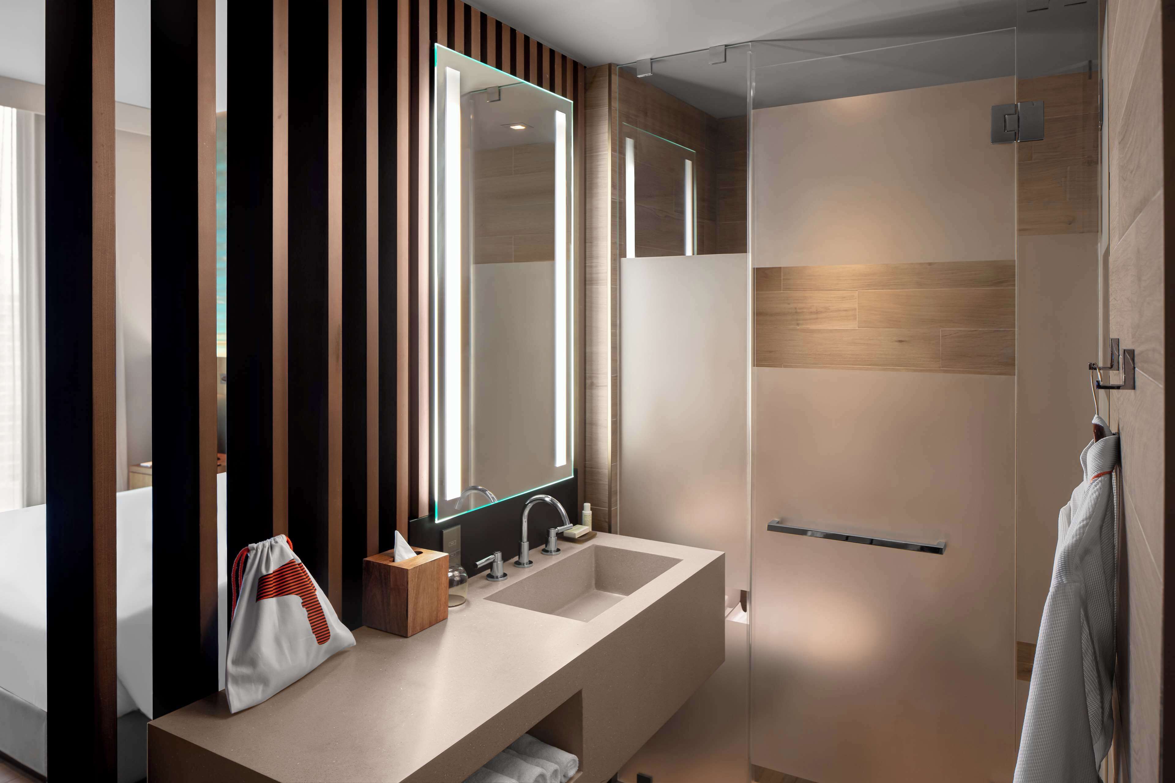 A modern bathroom with a large mirror, two sinks, and a walk-in shower.