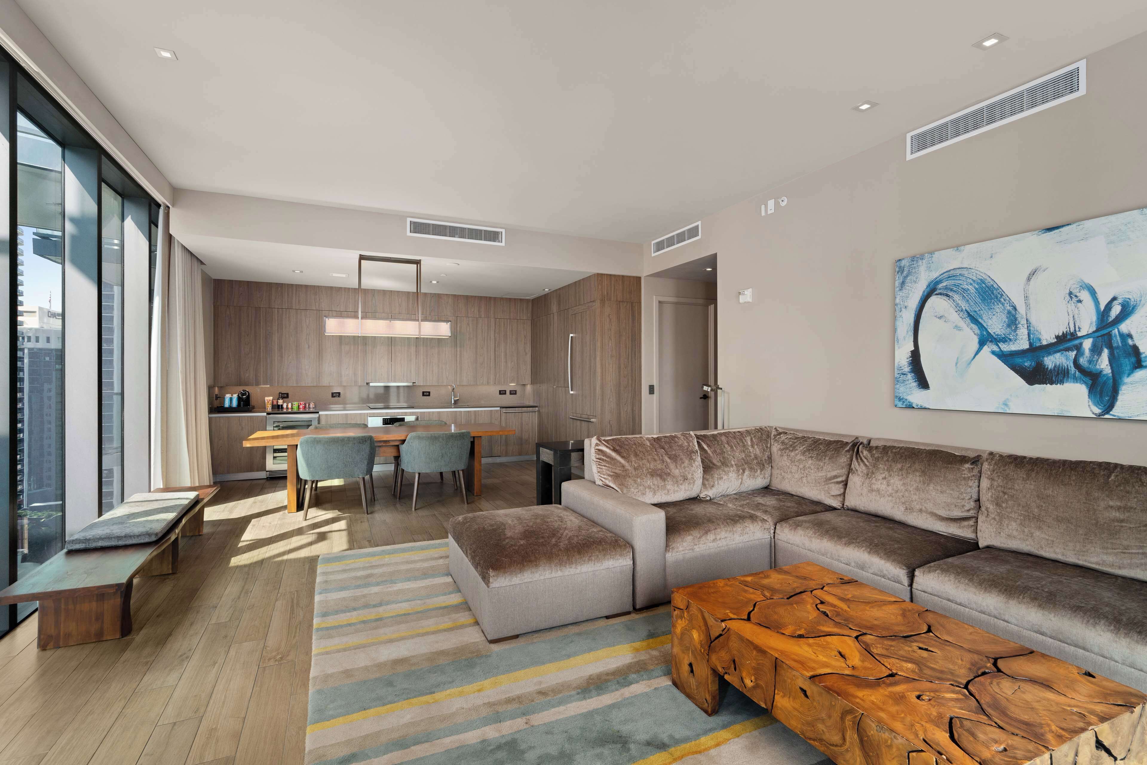 Una sala de estar moderna con un amplio sofá modular, una mesa de centro de madera y un tapete a rayas.