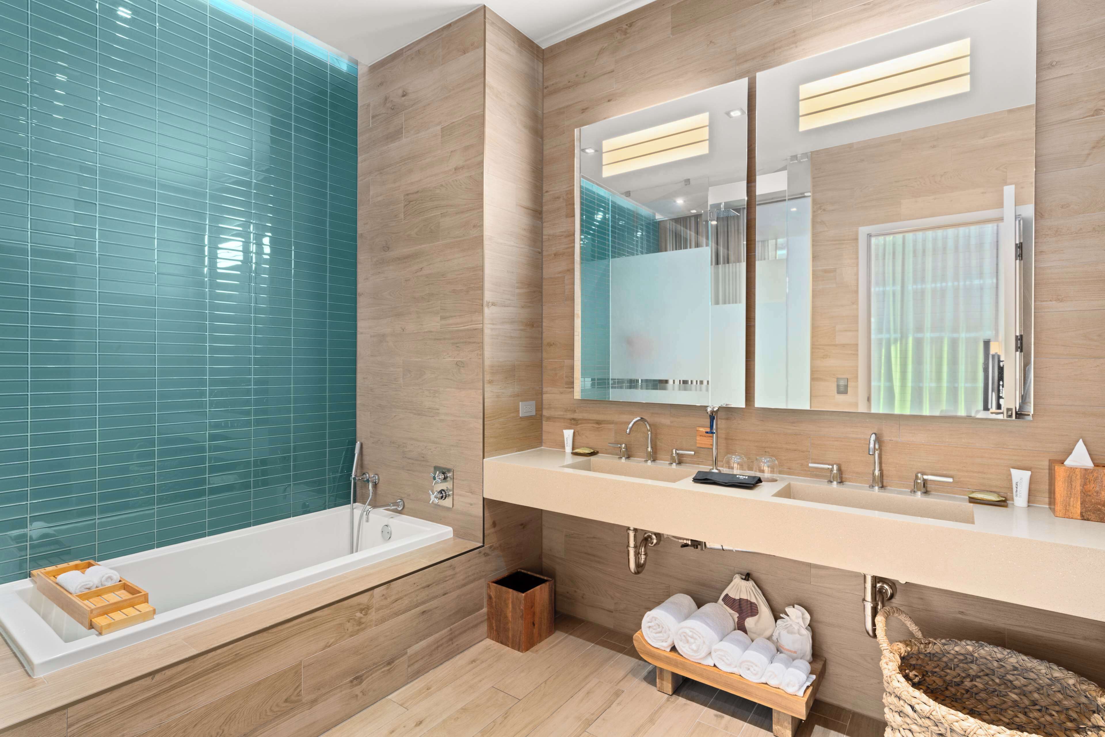 Un baño moderno con bañera, dos lavamanos y un espejo grande.