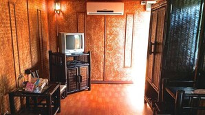 A room with a television on a wooden stand, a bench, and a cabinet. - Racha Herb Gardens (Saraphi)