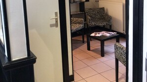 Une pièce avec un sol carrelé, une bibliothèque, des chaises à motifs et une table avec des magazines.