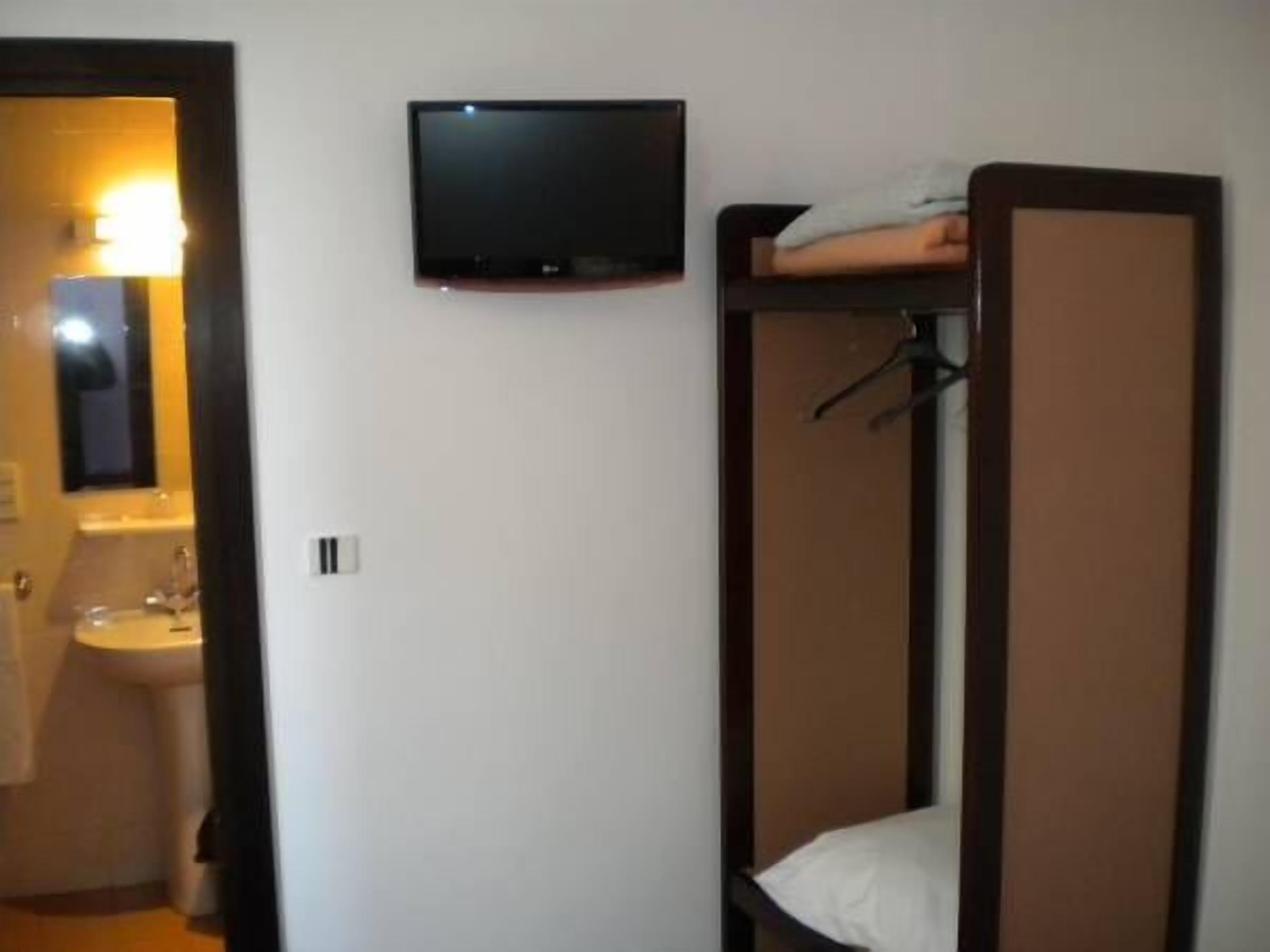 A small, compact room with a bunk bed, a television mounted on the wall, and a bathroom with a sink and mirror.