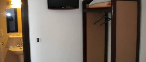 A small, compact room with a bunk bed, a television mounted on the wall, and a bathroom with a sink and mirror.