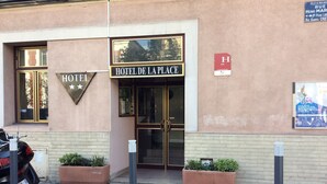 Un bâtiment sur lequel on peut lire l’inscription « HÔTEL DE LA PLACE » et, au-dessus, une enseigne indiquant simplement « HÔTEL ».