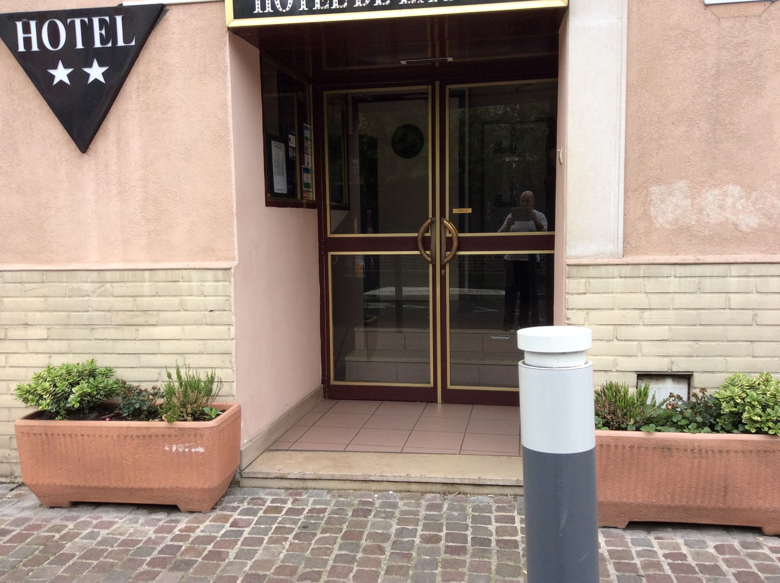 A hotel entrance with a glass door, a sign above the door, and two planters on either side.
