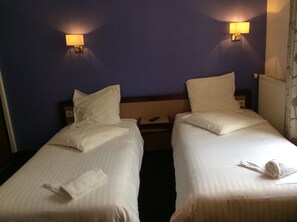 A hotel room with two single beds, each with a pillow and a rolled towel. - Hotel De La Place (Malakoff)