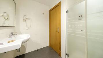 A bathroom with a white sink, a wooden door, and a glass shower enclosure.